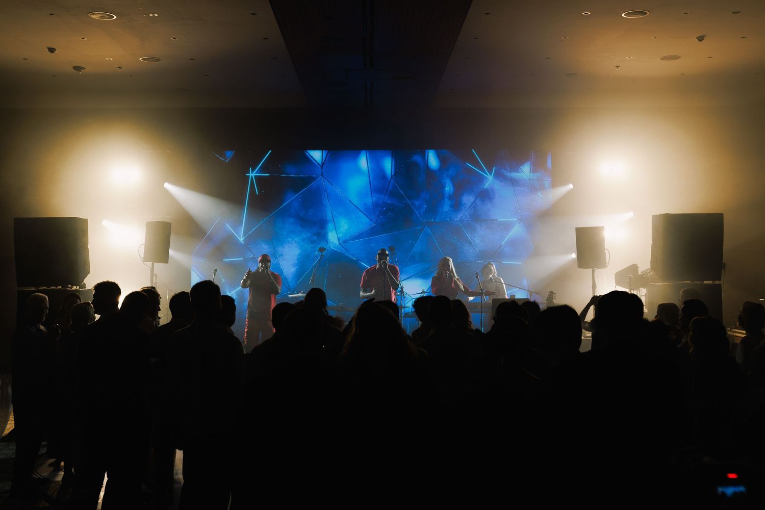 Silhouettes of party guests dancing under atmospheric lighting at a nighttime reception.