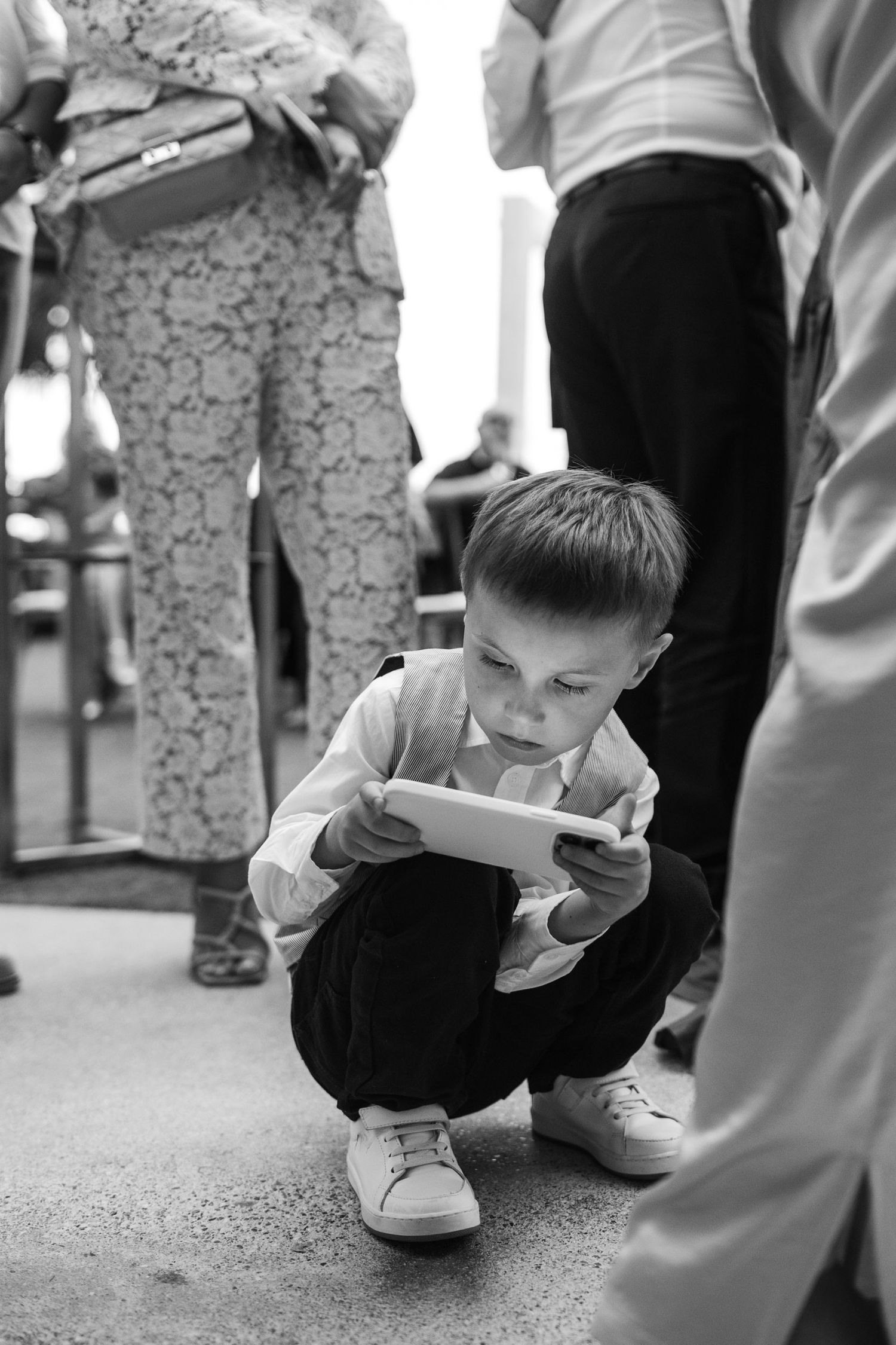 Young child in black attire crouching down during a formal event.