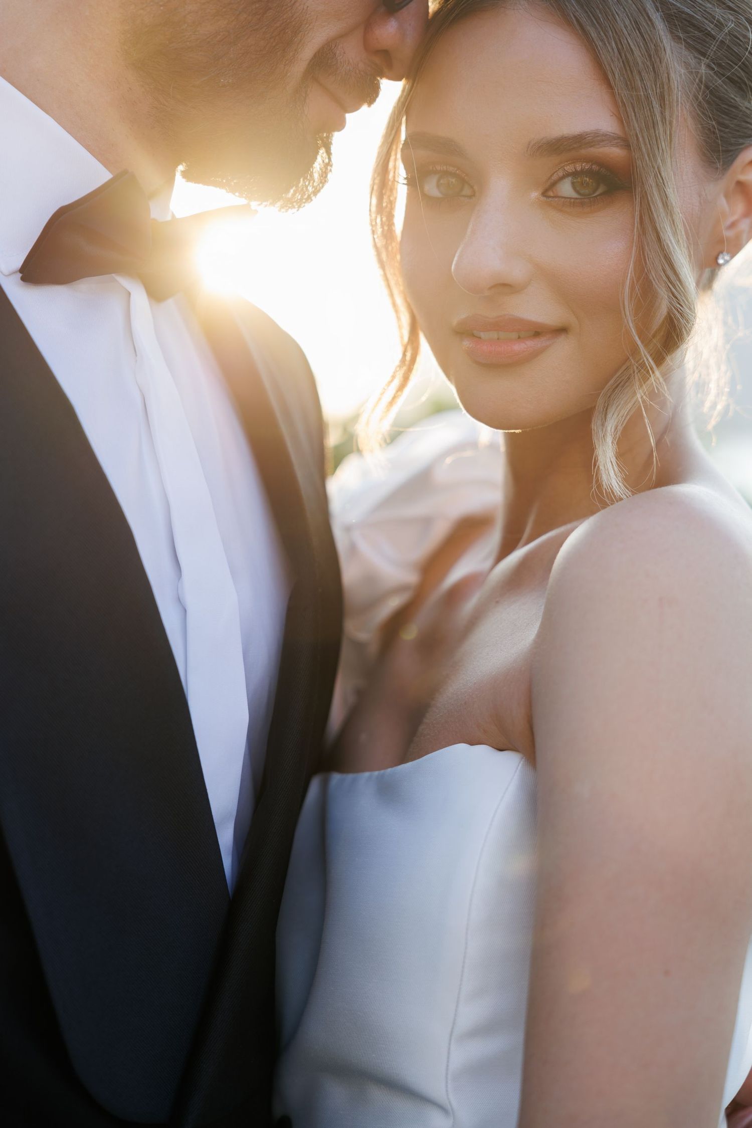Soft sunlit wedding portraits capture tender moments between newlyweds.