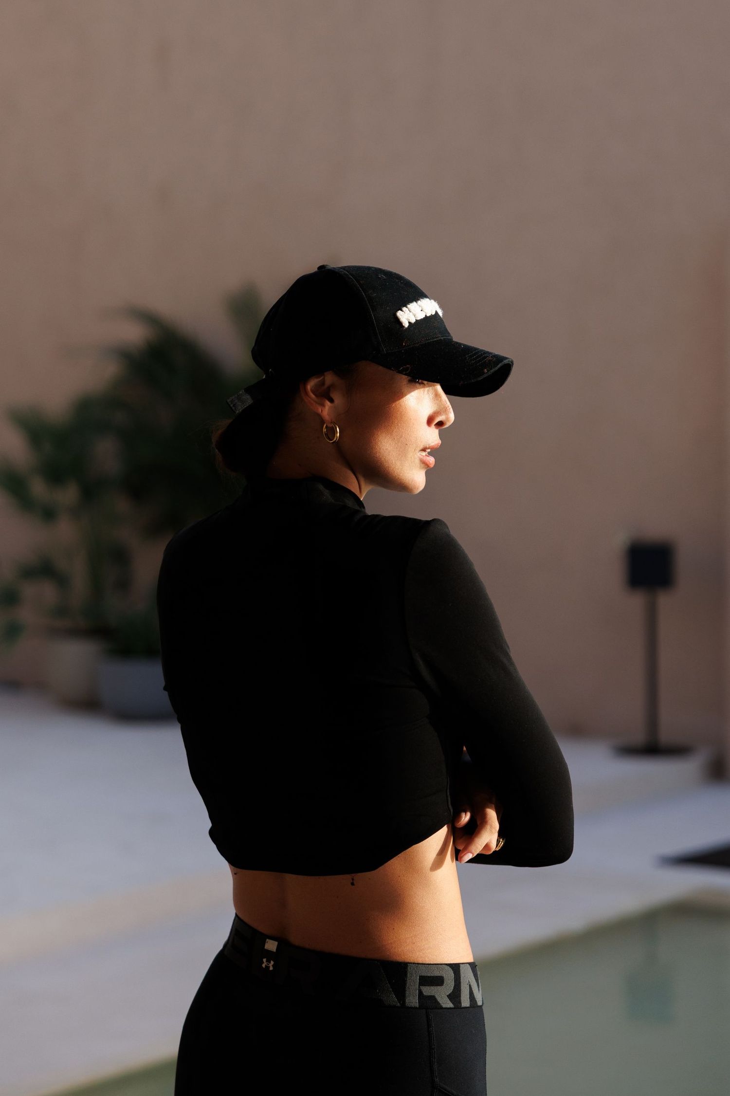 Athletic figure in black activewear and baseball cap photographed in silhouette.