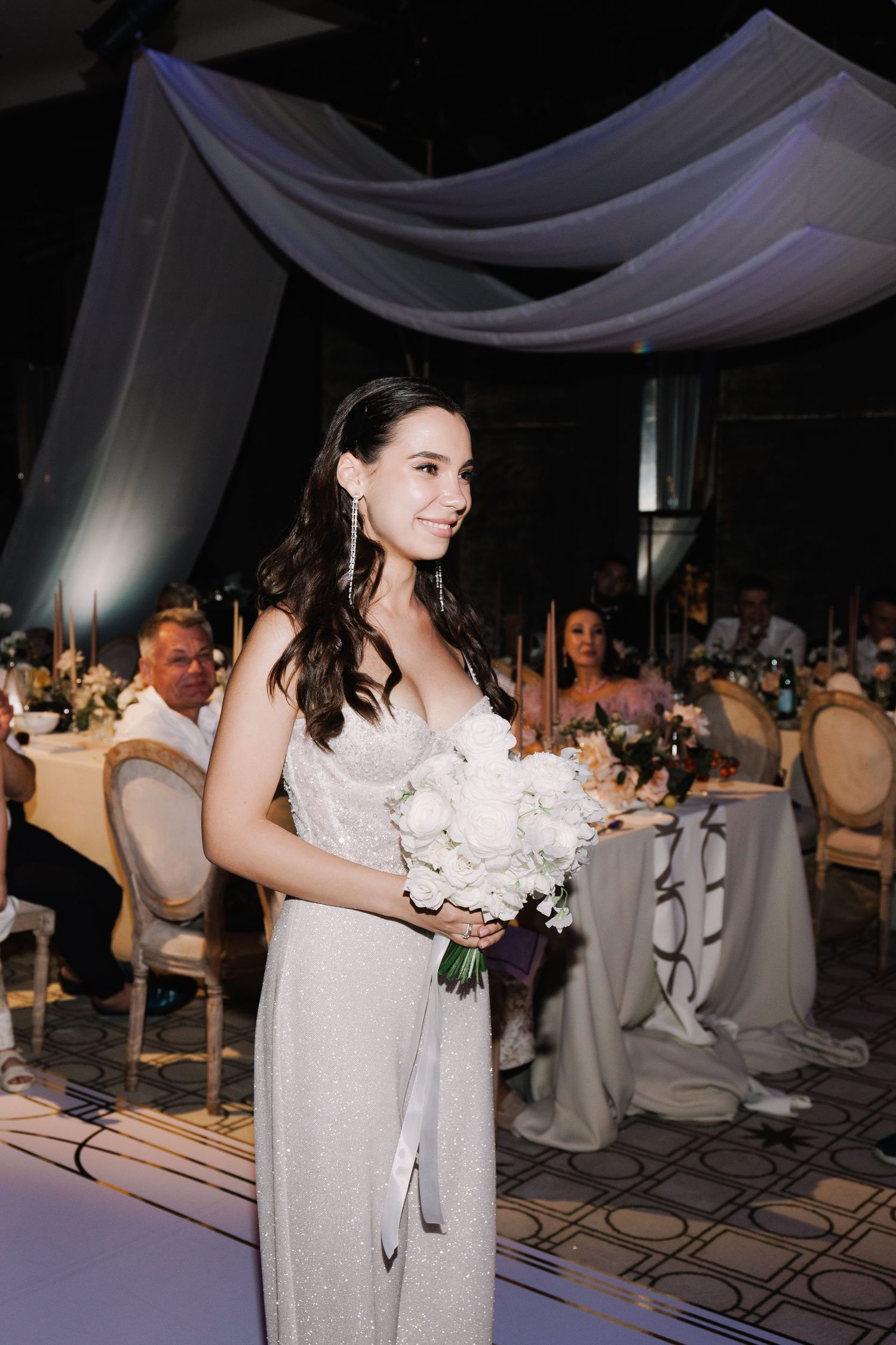 Reception venue with white draping and elegant table settings.