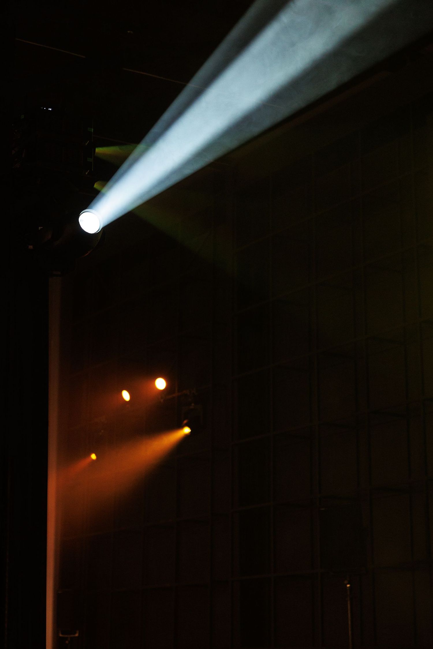 Dramatic stage lighting with white beams cutting through darkness.