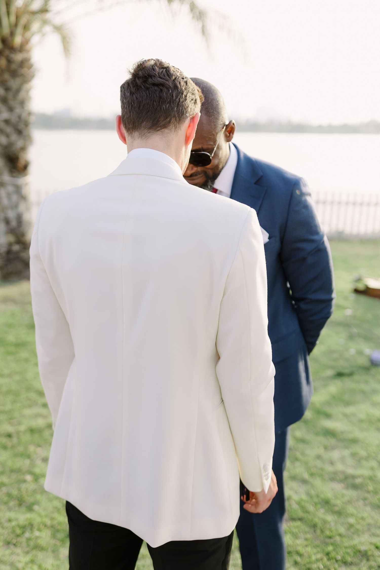 People in formal suits standing on grass during an outdoor event.