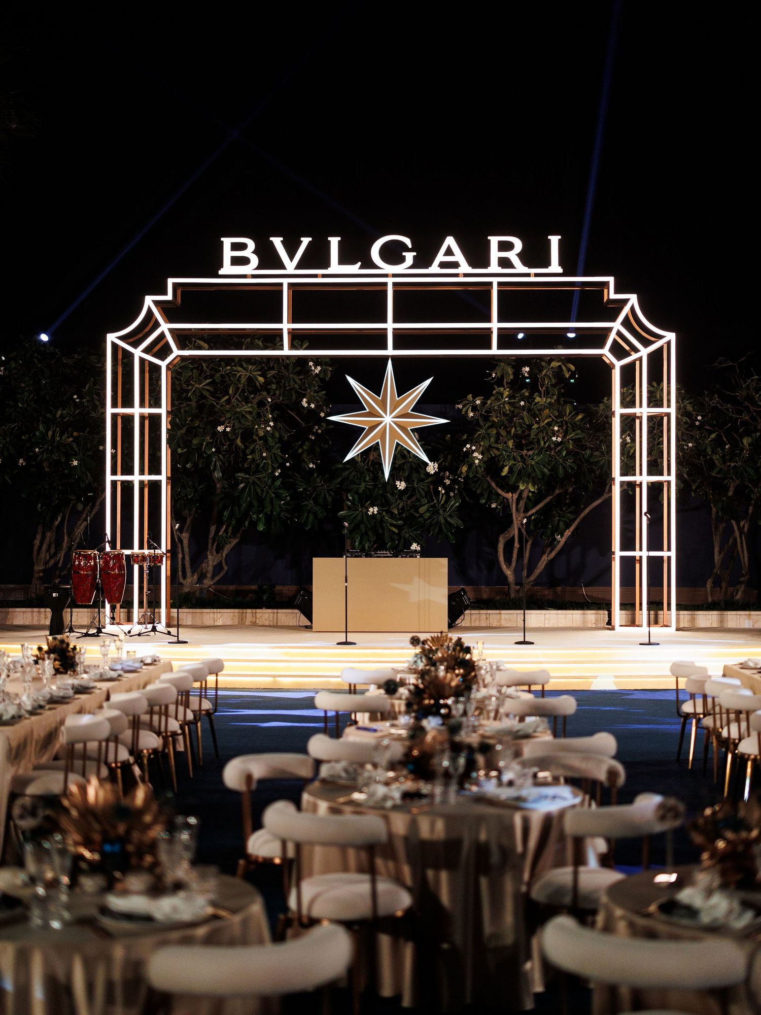 Elegant event venue setup with BVLGARI branding and decorative star motifs illuminating multiple dining tables.