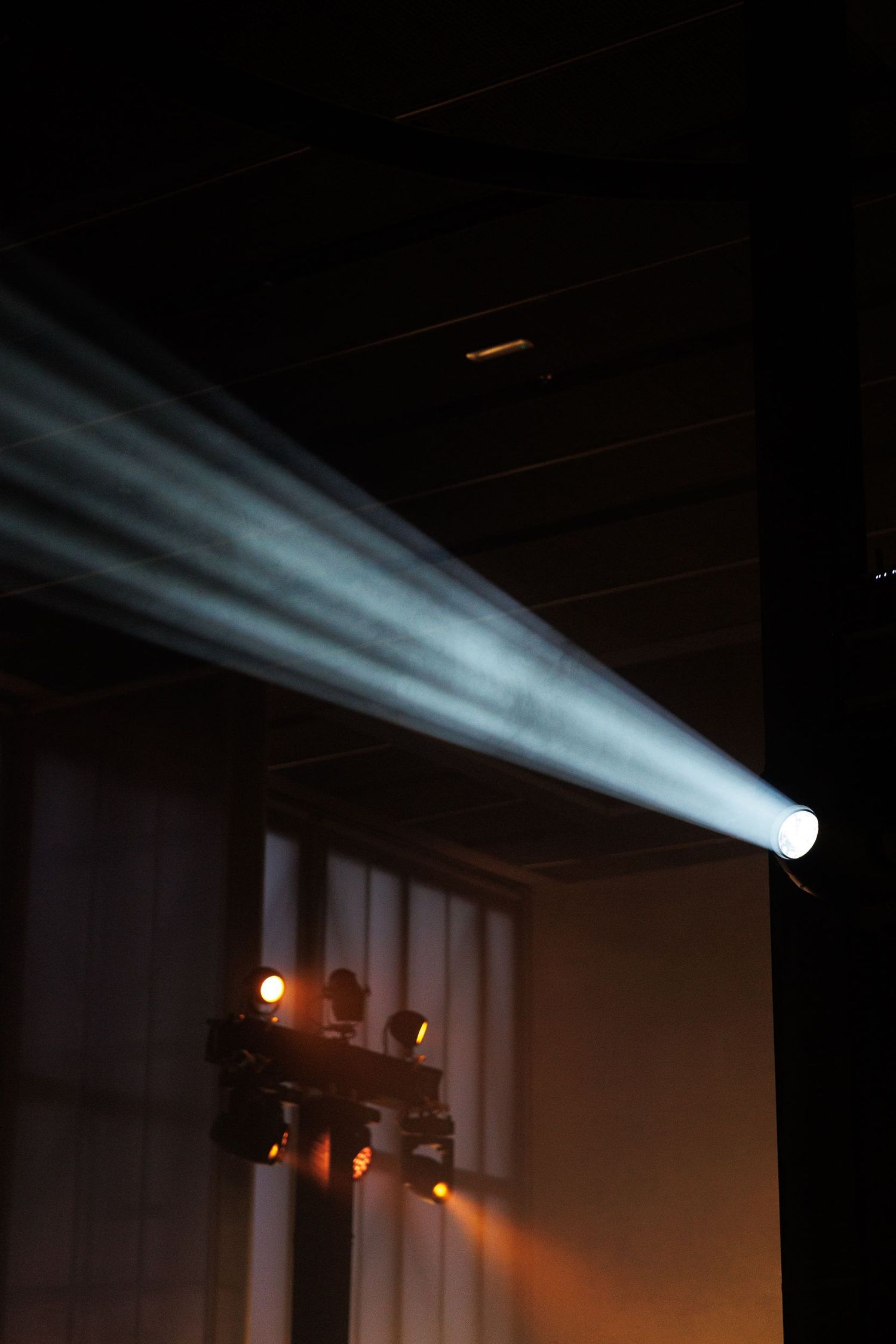 Theatrical lighting beams creating dramatic atmosphere in dark space.