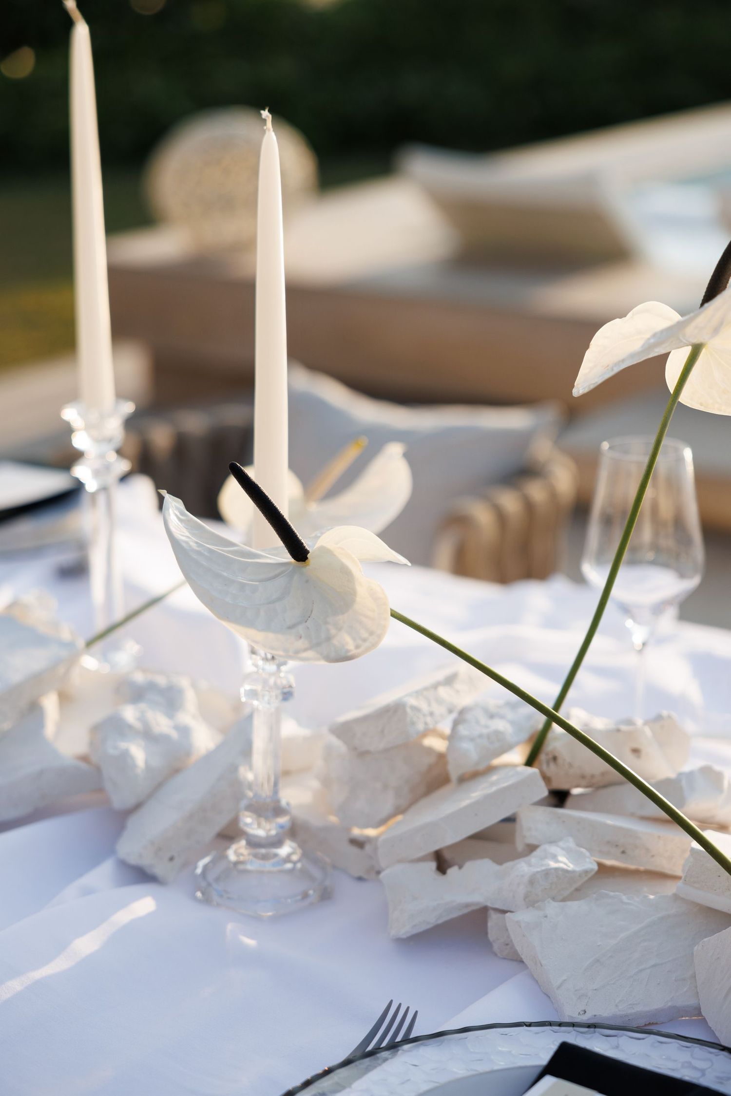 Elegant white table settings with taper candles and floral decorations for a wedding reception.