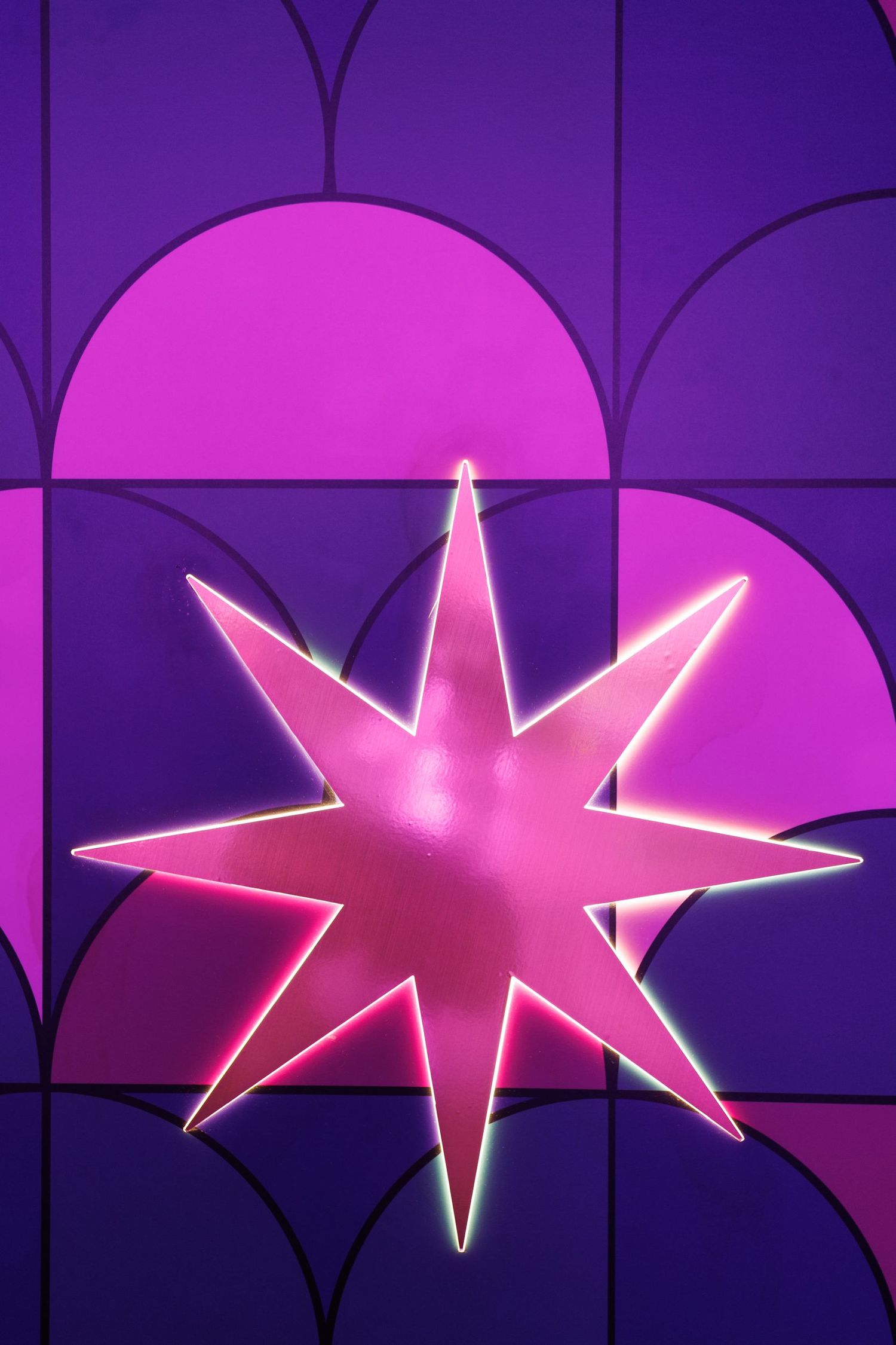 Illuminated pink star-shaped lights mounted on a purple wall creating a geometric pattern.