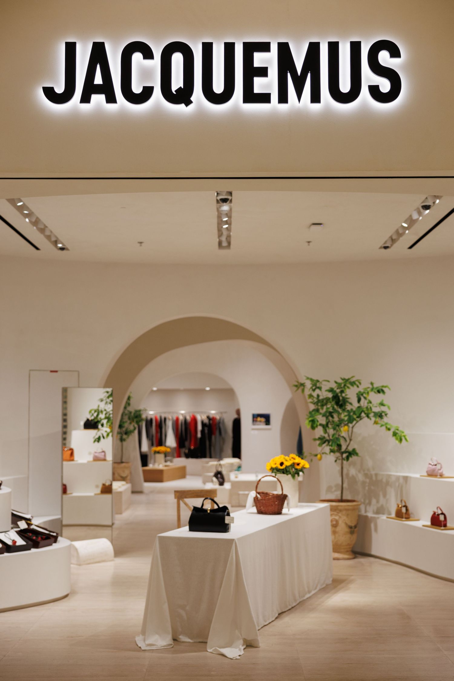 Modern boutique interior featuring JACQUEMUS branding and clean white display areas.