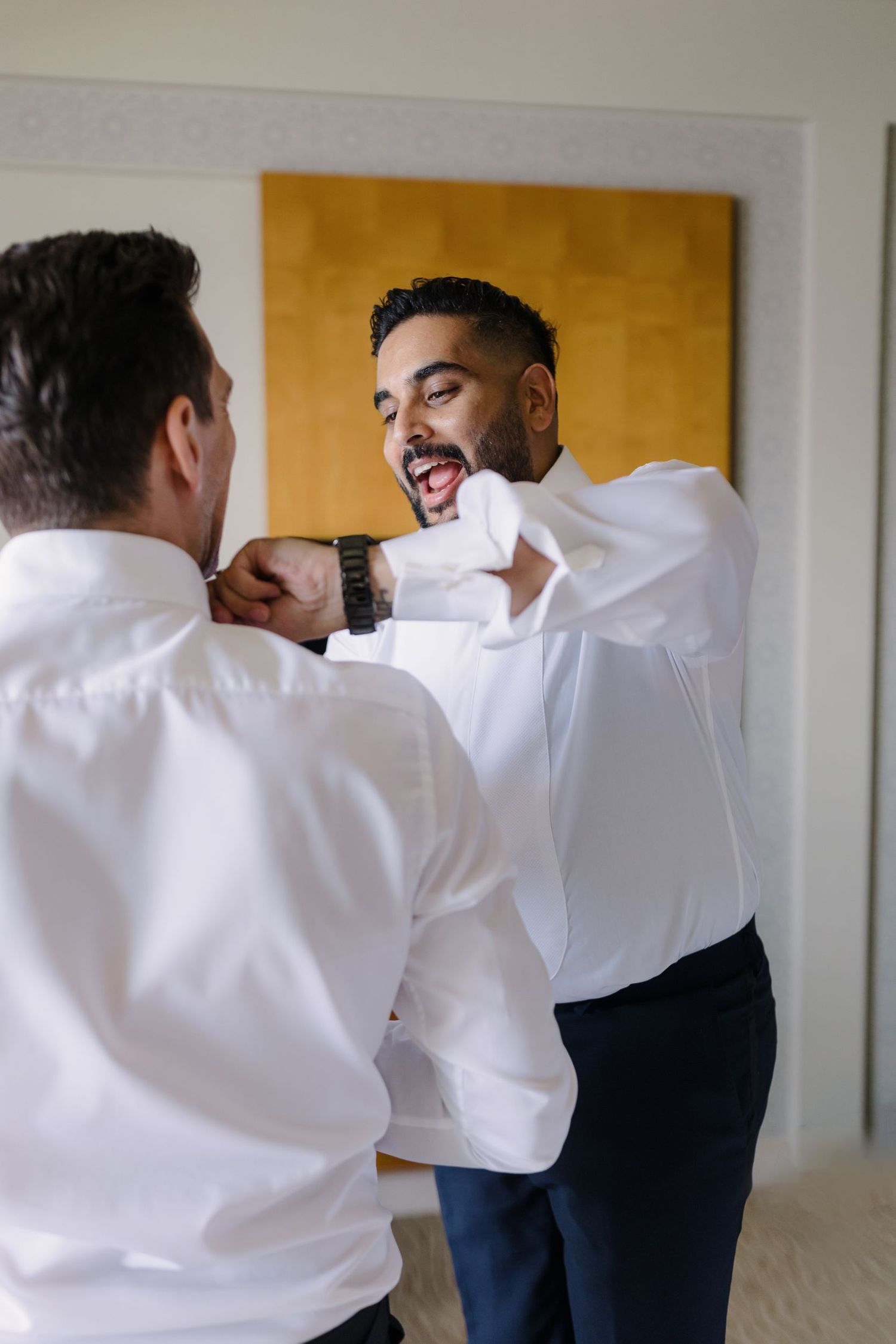 Groomsmen in white shirts and navy pants getting ready before the wedding.