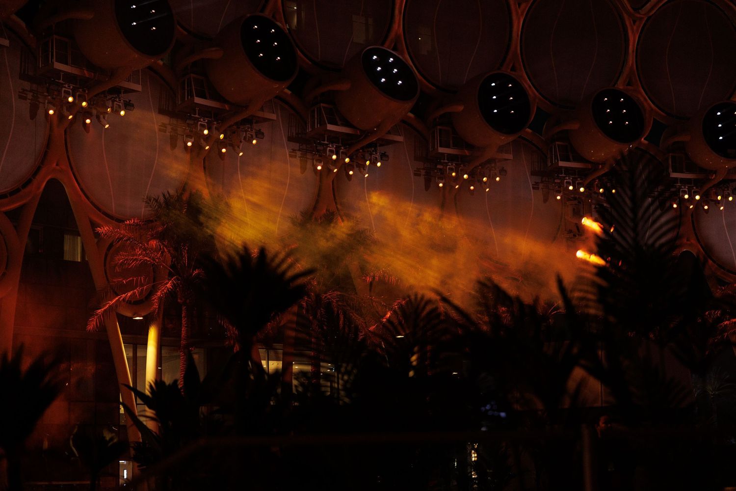 Dramatic orange and red lighting illuminates an outdoor evening event space.