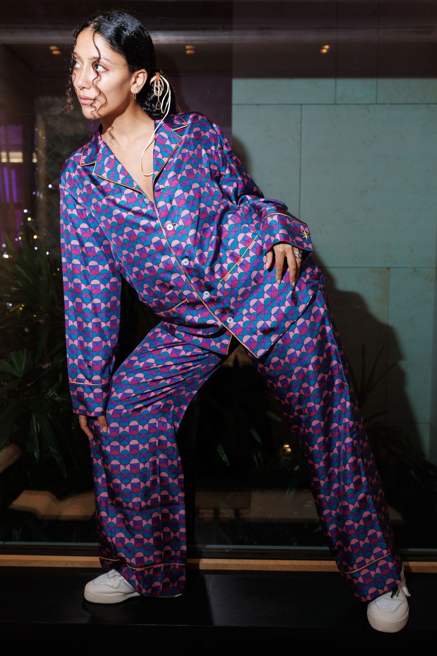 Figure in blue patterned pajamas strikes dynamic poses against a wall.