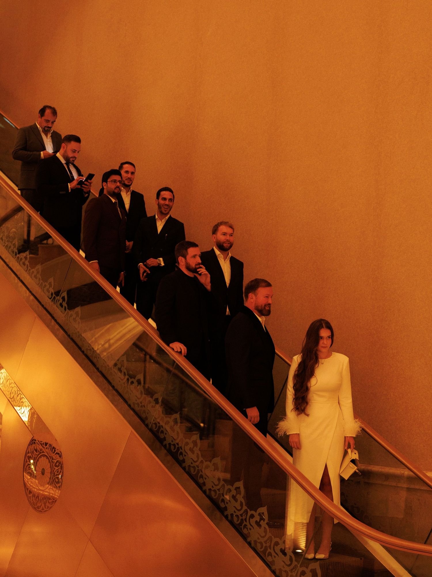 Formal event guests descending an ornate staircase with warm lighting and elegant decor.