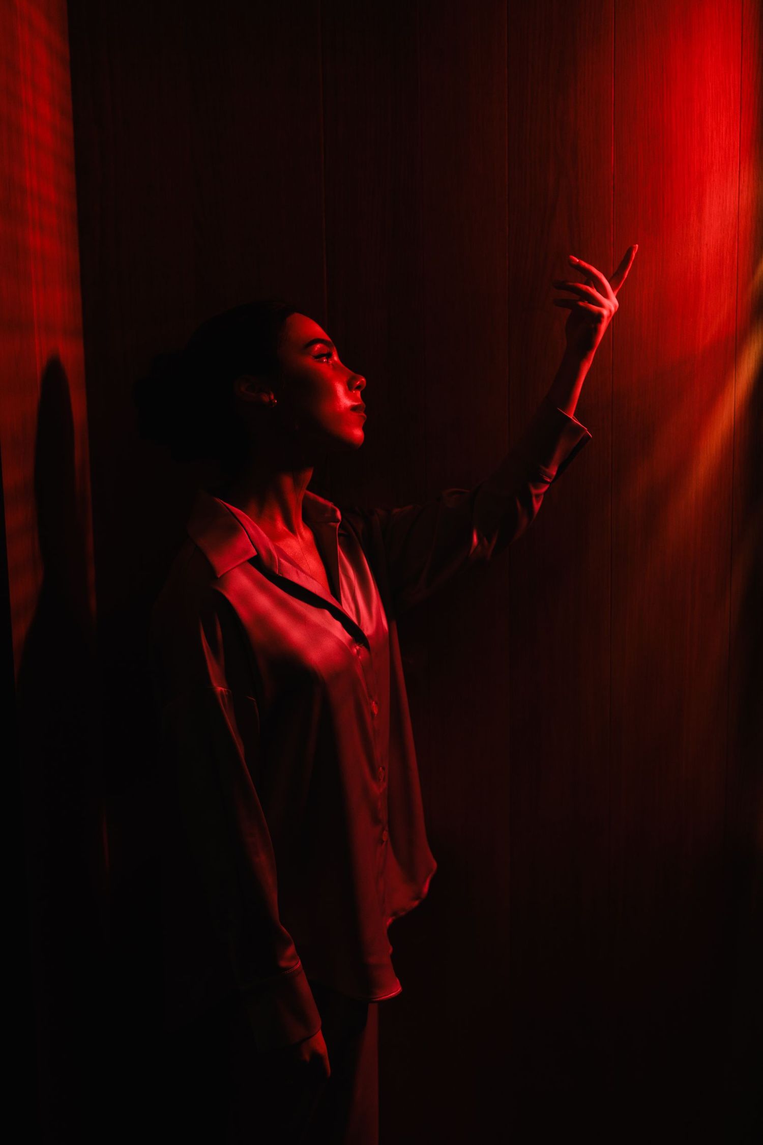 Silhouette in red lighting with arm raised against dark background.
