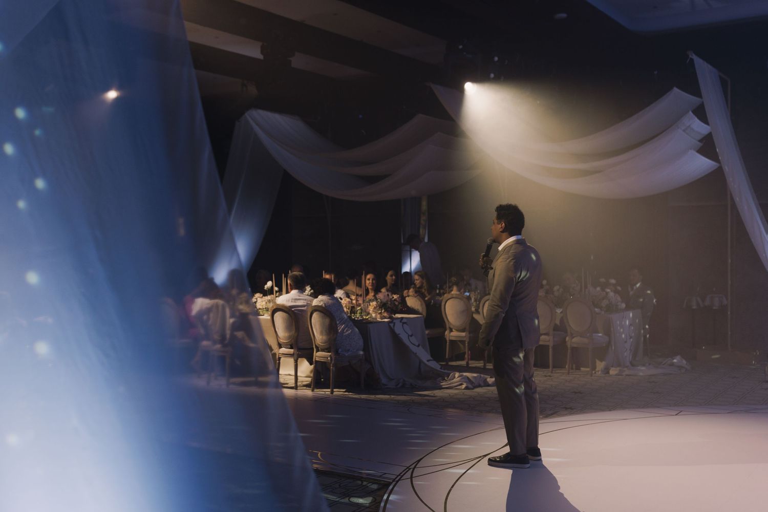Atmospheric wedding reception venue with dramatic lighting and dancing silhouettes.