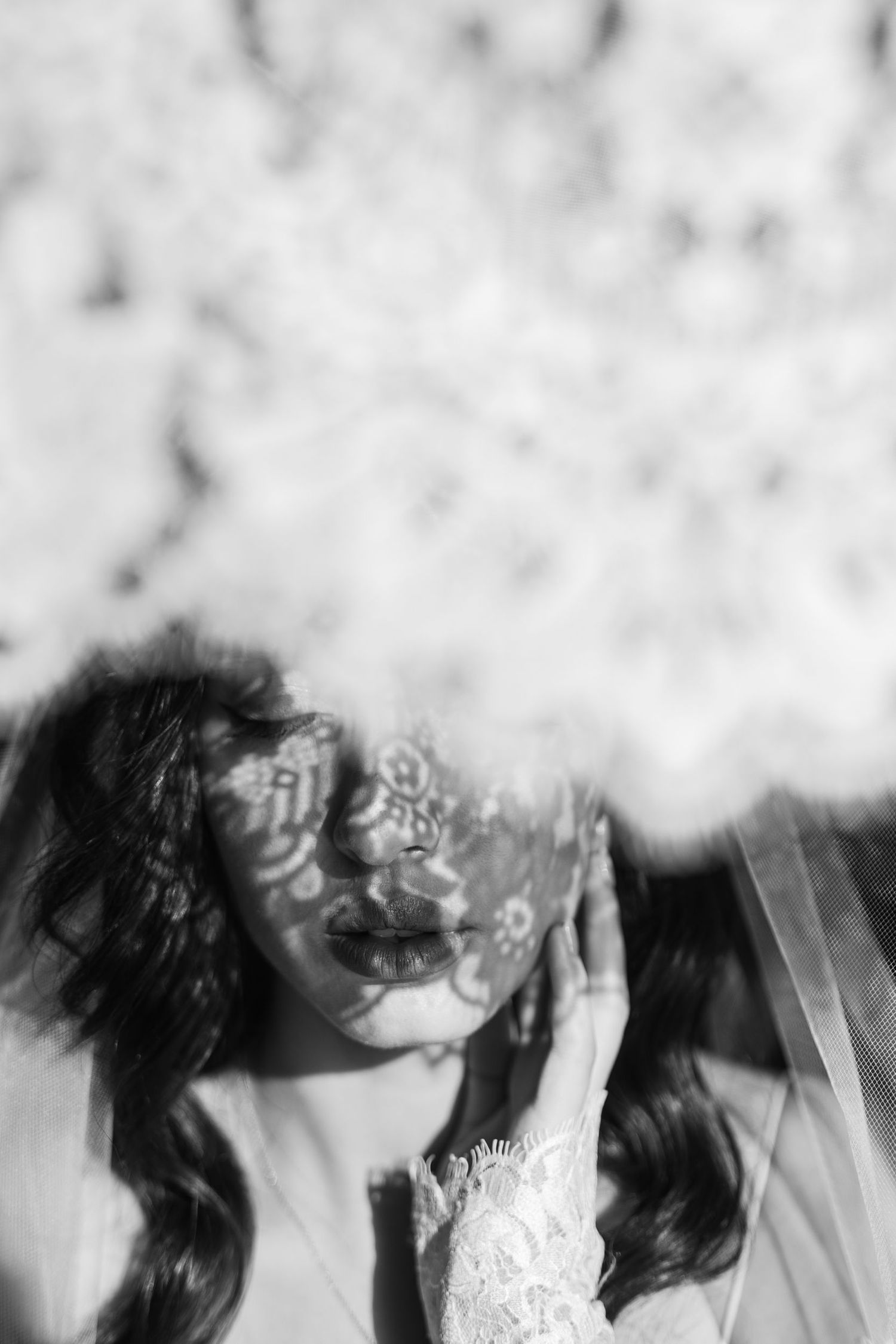 Artistic black and white photo of a bride with flowing veil creating a dreamy effect.