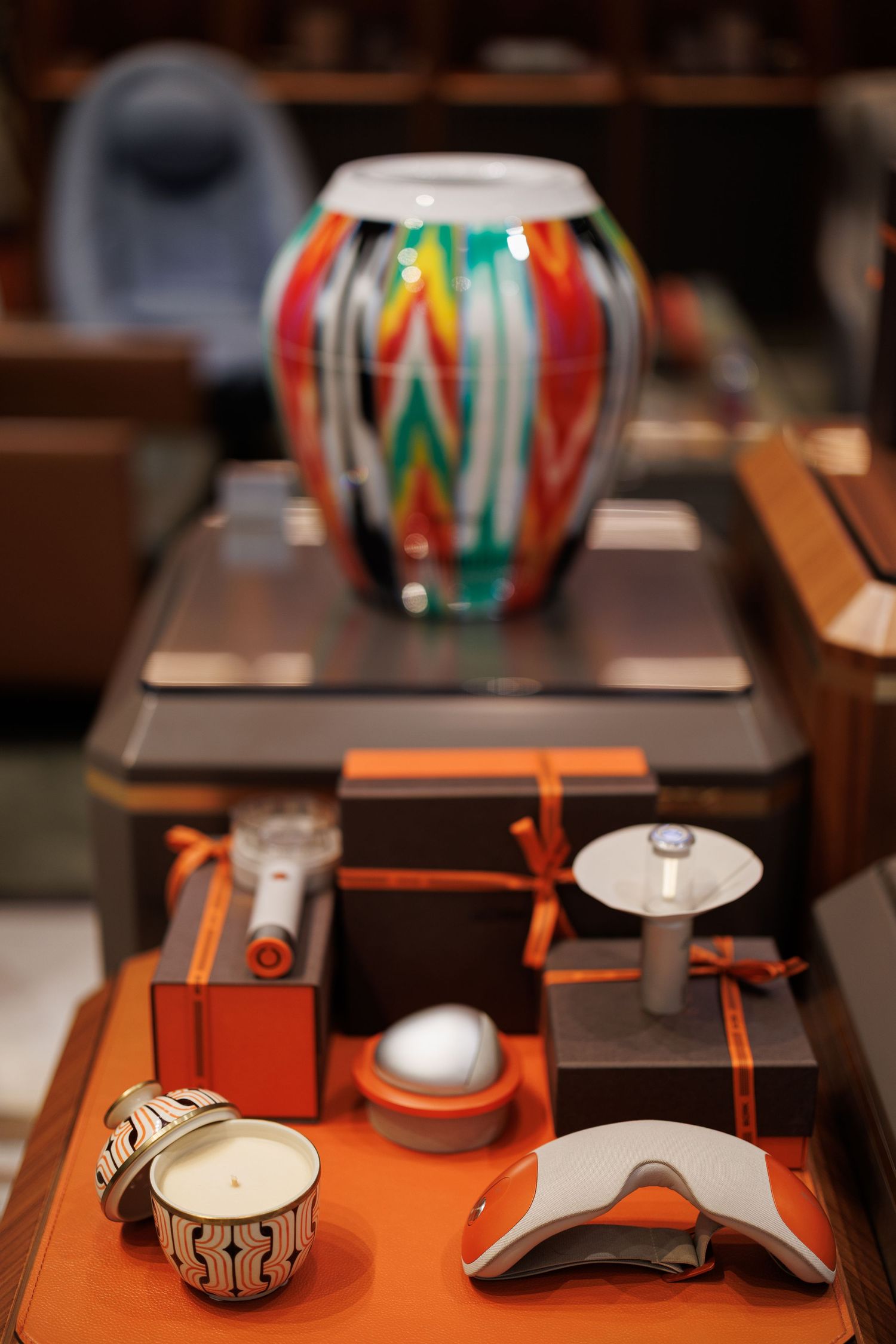 Orange and metallic accessories and decorative items arranged on dark display tables.