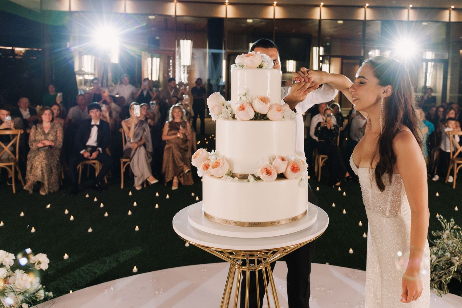 Wedding reception venue with string lights and guests gathered around a dance floor.