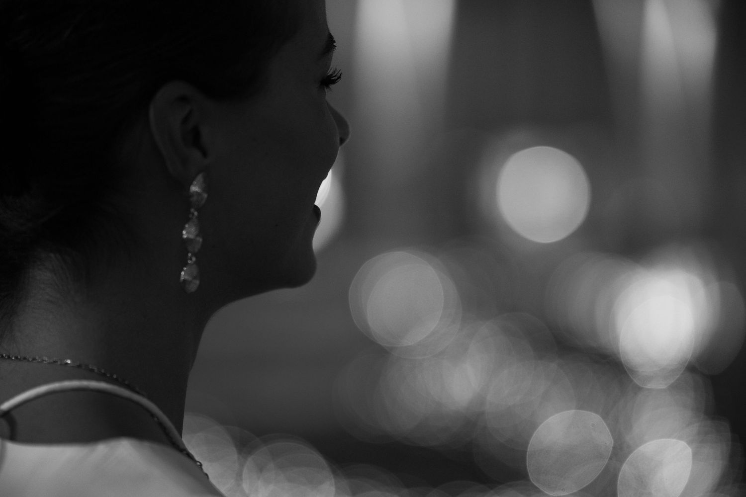 Artistic black and white portrait with soft bokeh lighting effects in the background.