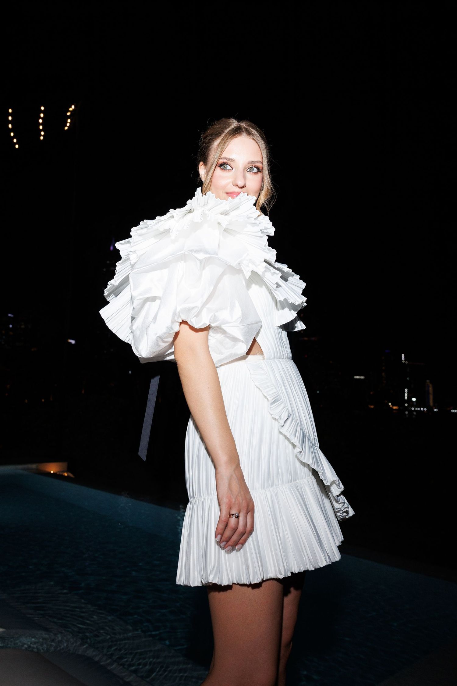 Short white ruffled dress photographed against dark background at night.