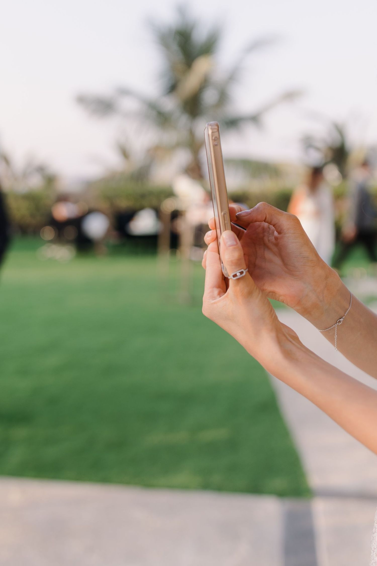 Hands holding sparklers against a green lawn backdrop at an outdoor event.