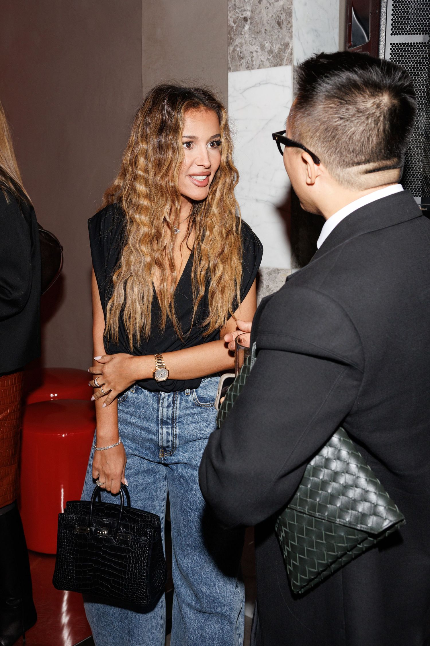 Candid party scene with people interacting, featuring denim and black outfits.