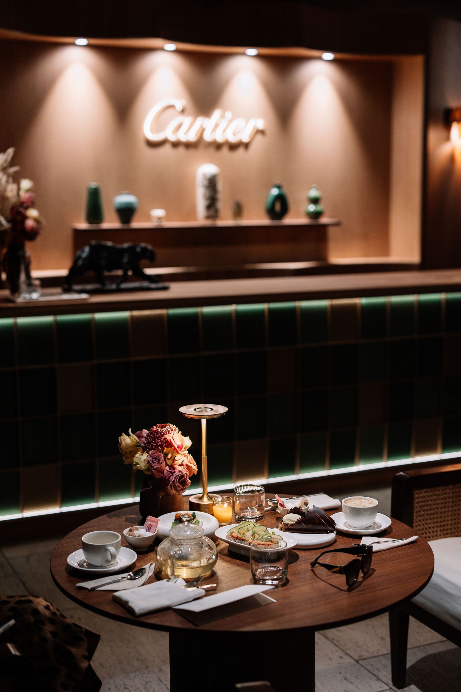 Modern restaurant interior with dark wood tables and ambient lighting showcases elegant table settings and food presentation.