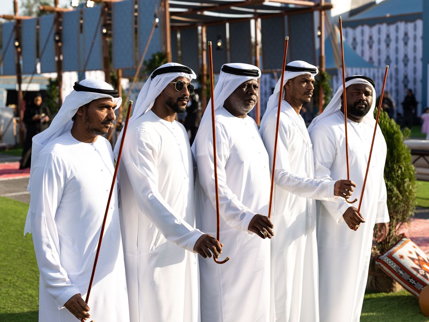 A group in traditional white kandura robes and headwear standing together at an outdoor event.