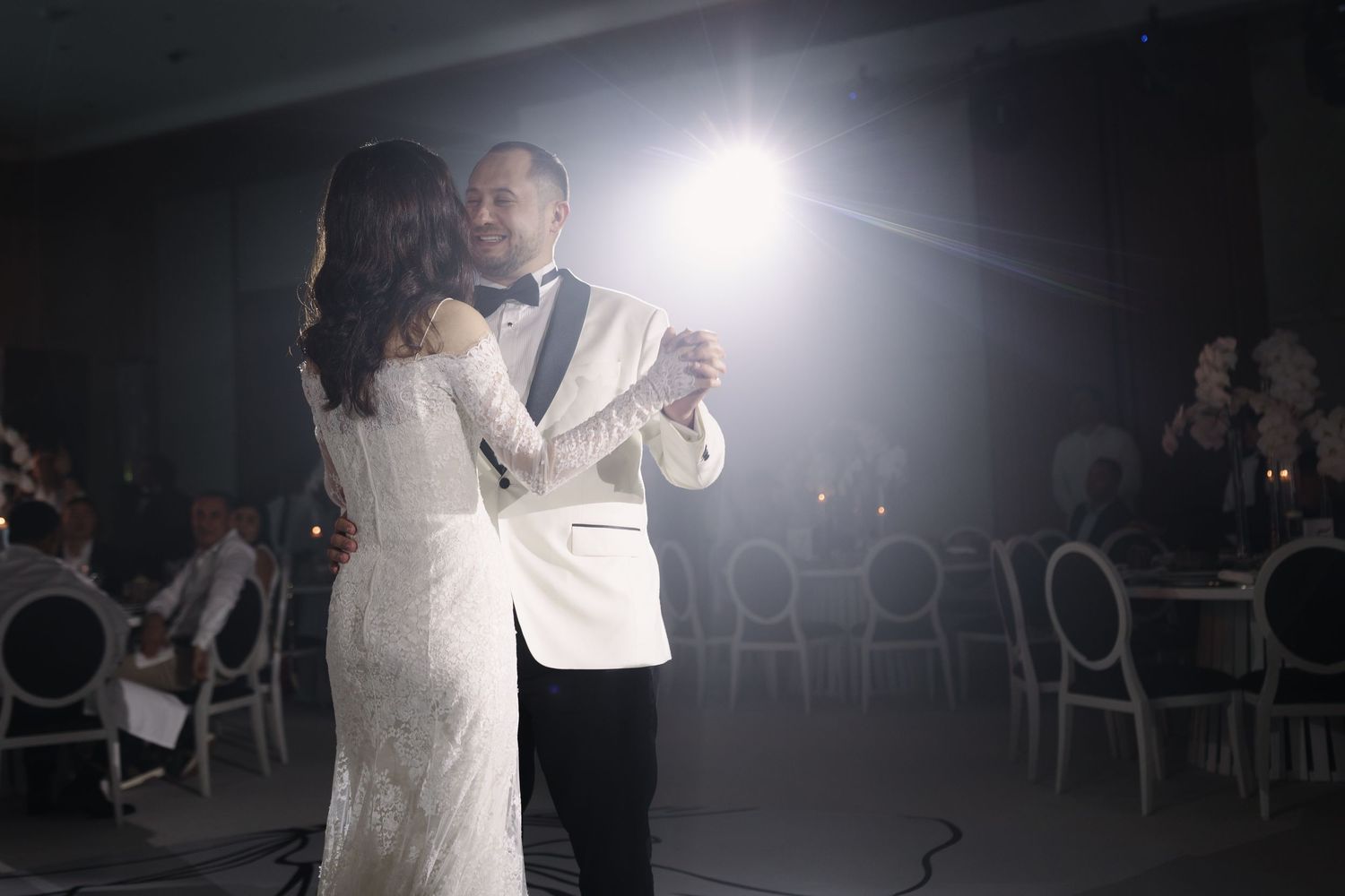 Wedding dance floor scene with dramatic spotlight effects in dark reception venue.