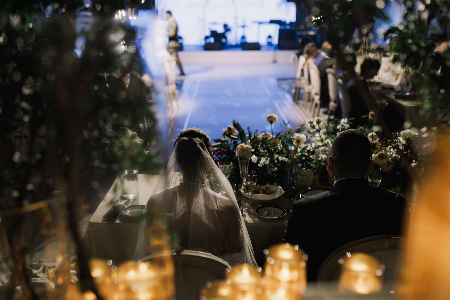 Elegant wedding reception table decorated with hanging lights, greenery, and floral arrangements.