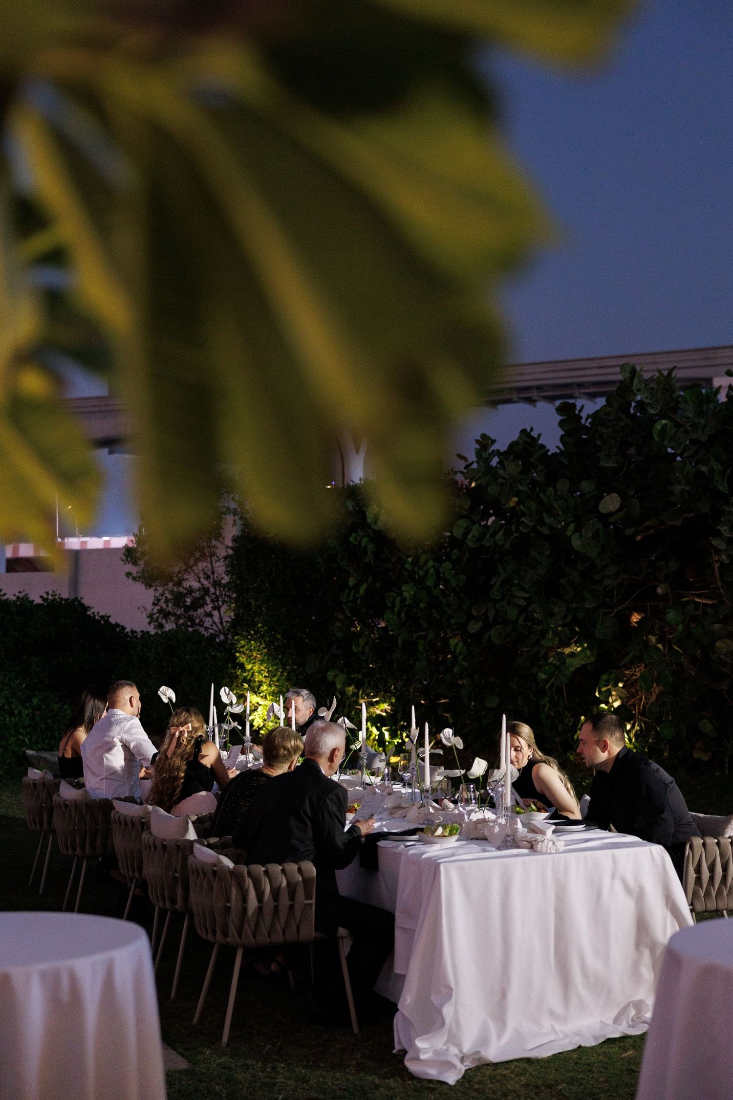 Intimate outdoor wedding reception tables lit by ambient lighting at night.
