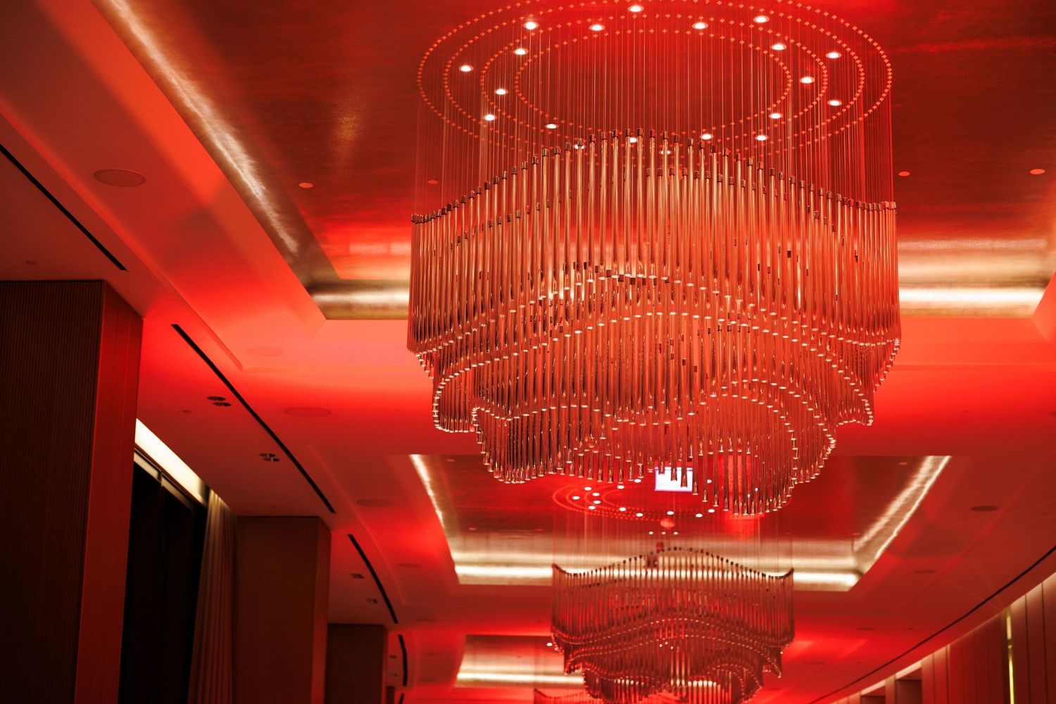 Elegant chandelier illuminated with red lighting in an upscale venue ceiling.