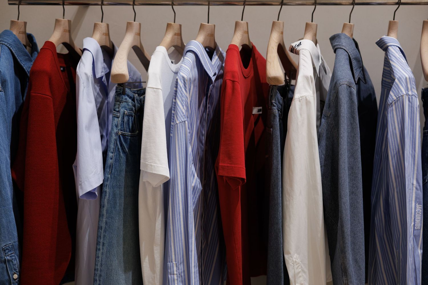 Row of colorful shirts and jackets hanging on a clothing rack.