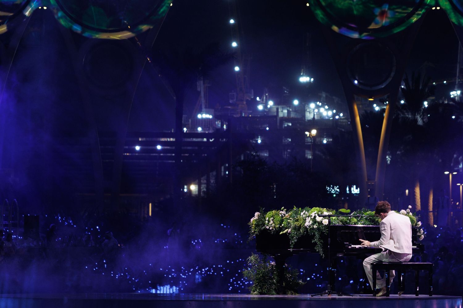 Nighttime performance venue with twinkling lights and green foliage decorations.