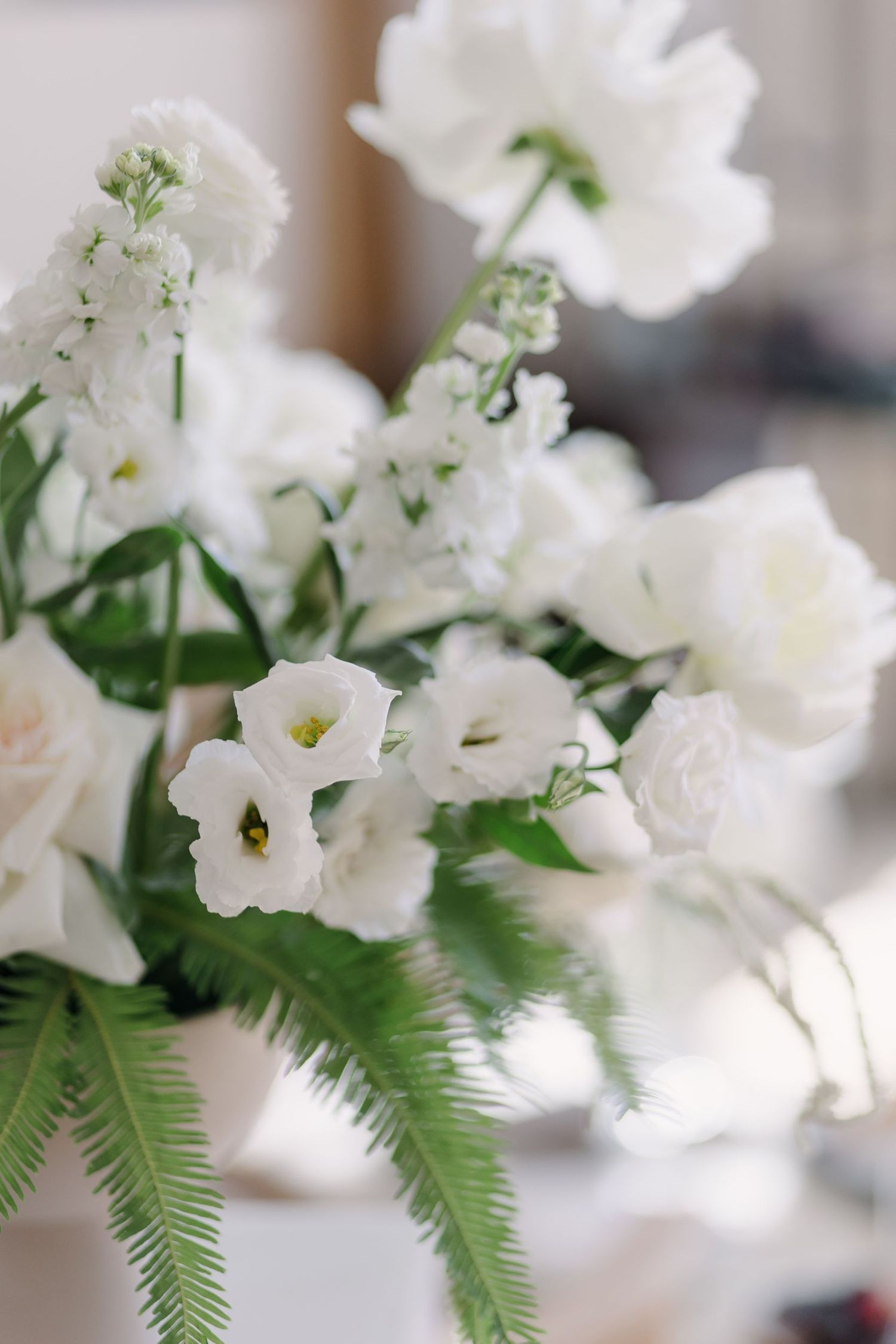 White delicate flowers and ferns arranged in an elegant wedding centerpiece.