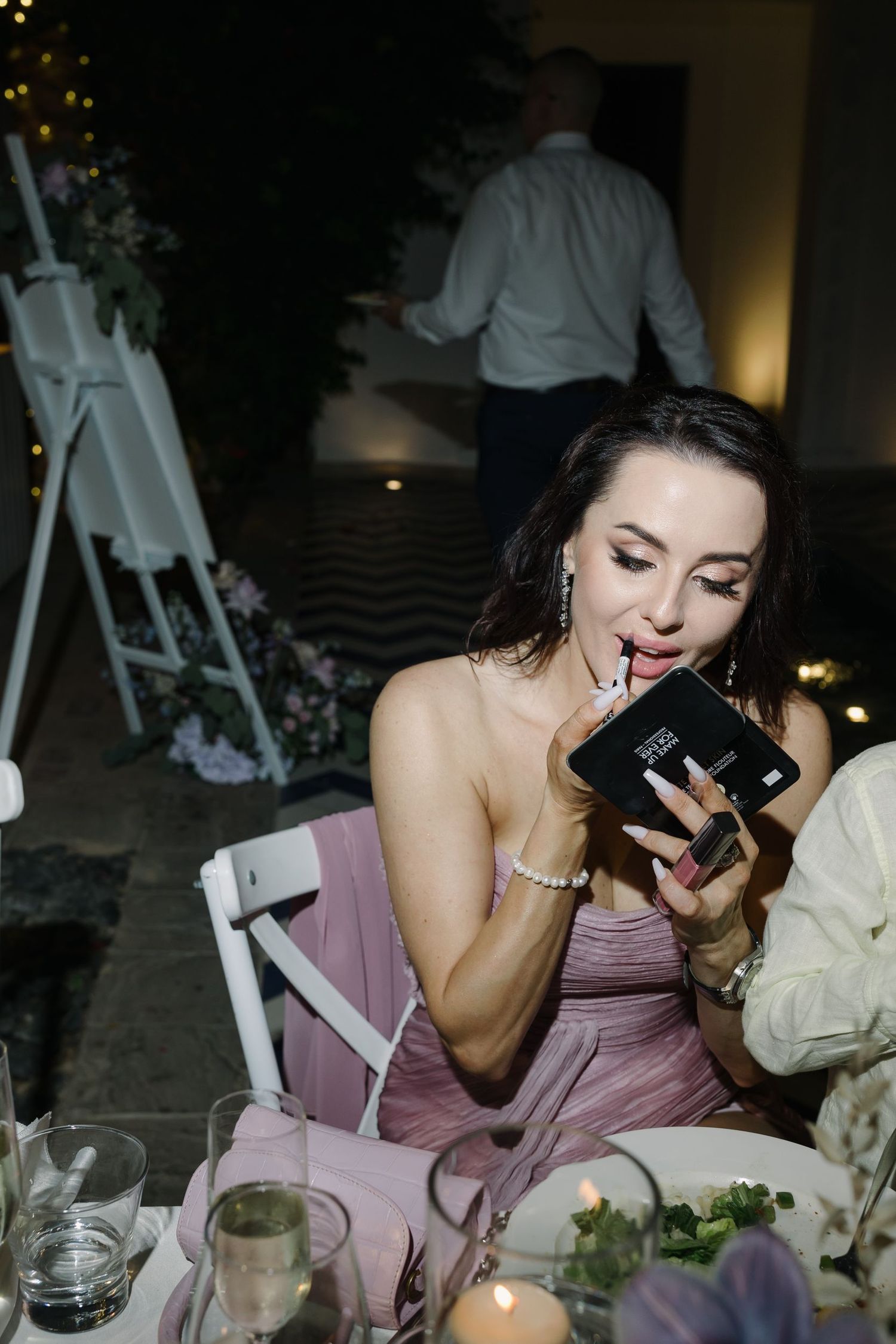 Wedding guest in mauve dress laughing during reception dinner.