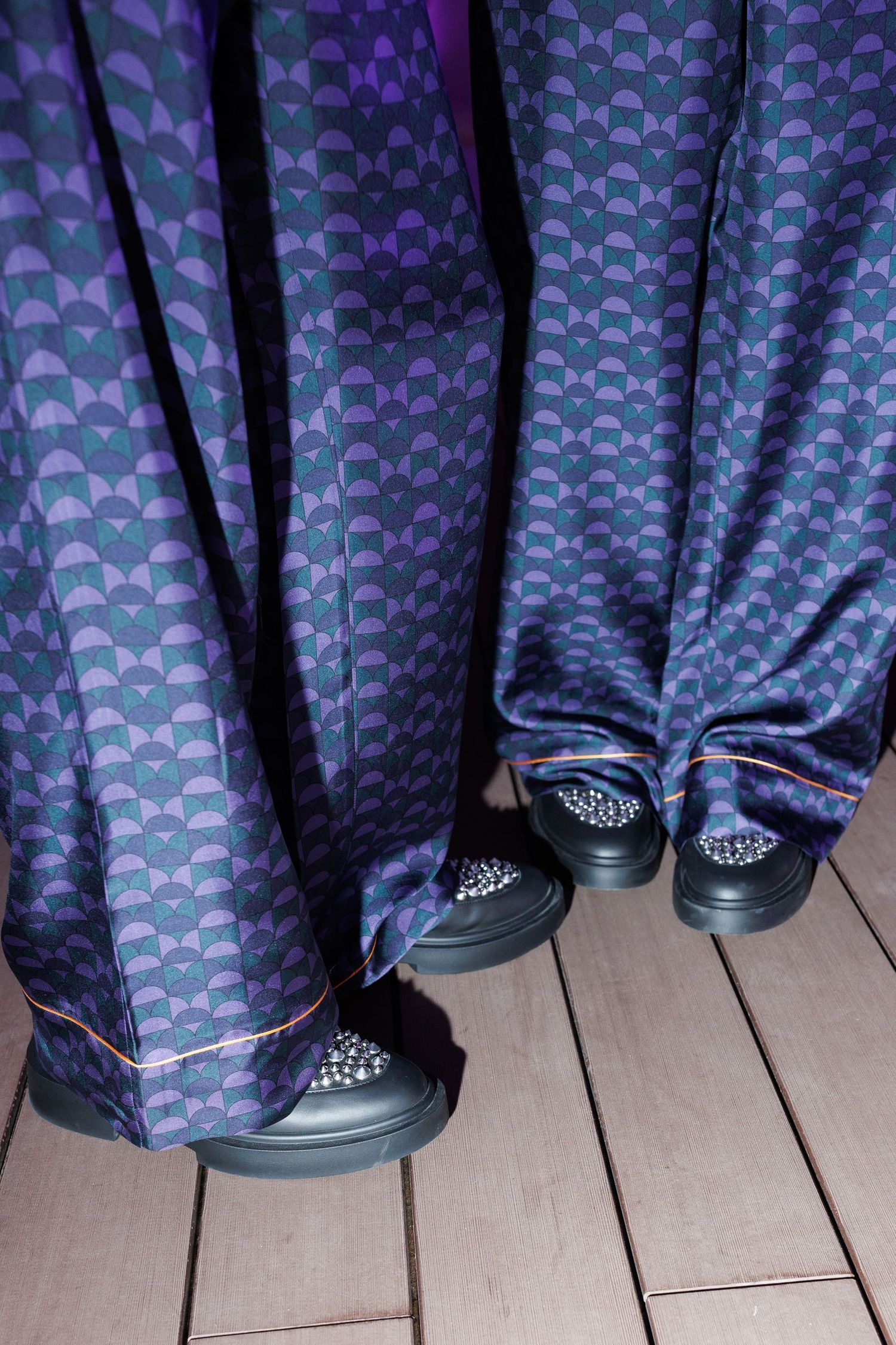 Close-up of patterned blue fabric and black shoes on wooden decking.