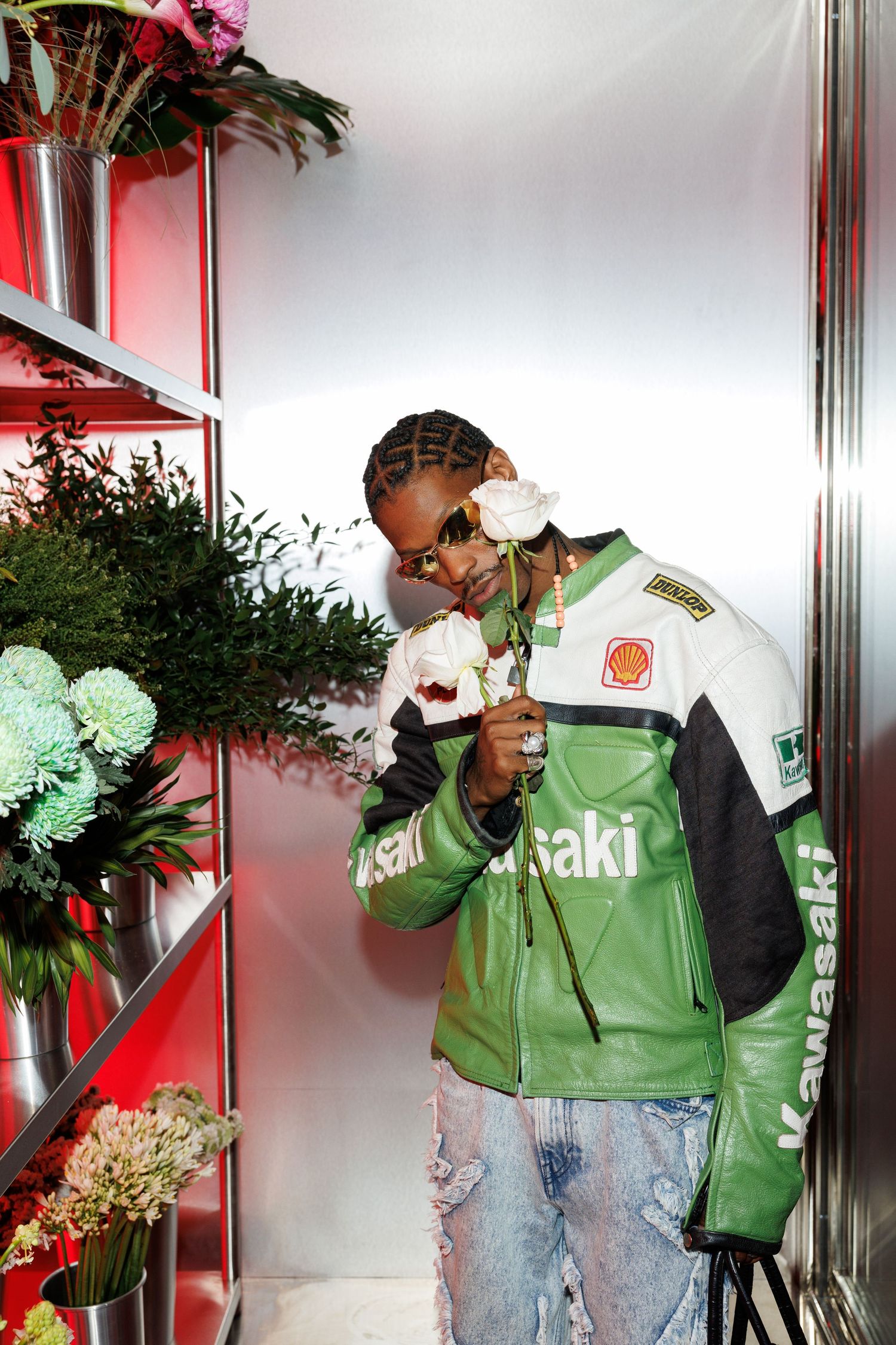 People in green uniforms arranging flowers in a bright white display area.