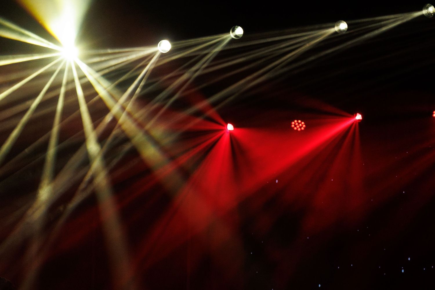 Stage lighting creates dramatic yellow and white beam patterns against a dark background.