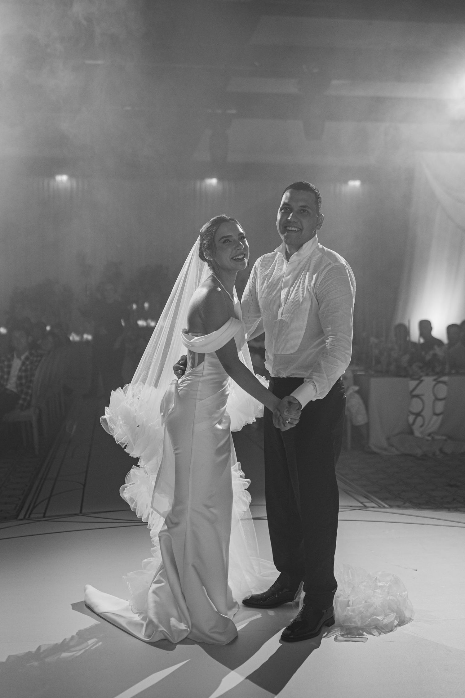 Couple dancing together on illuminated white dance floor at wedding reception.