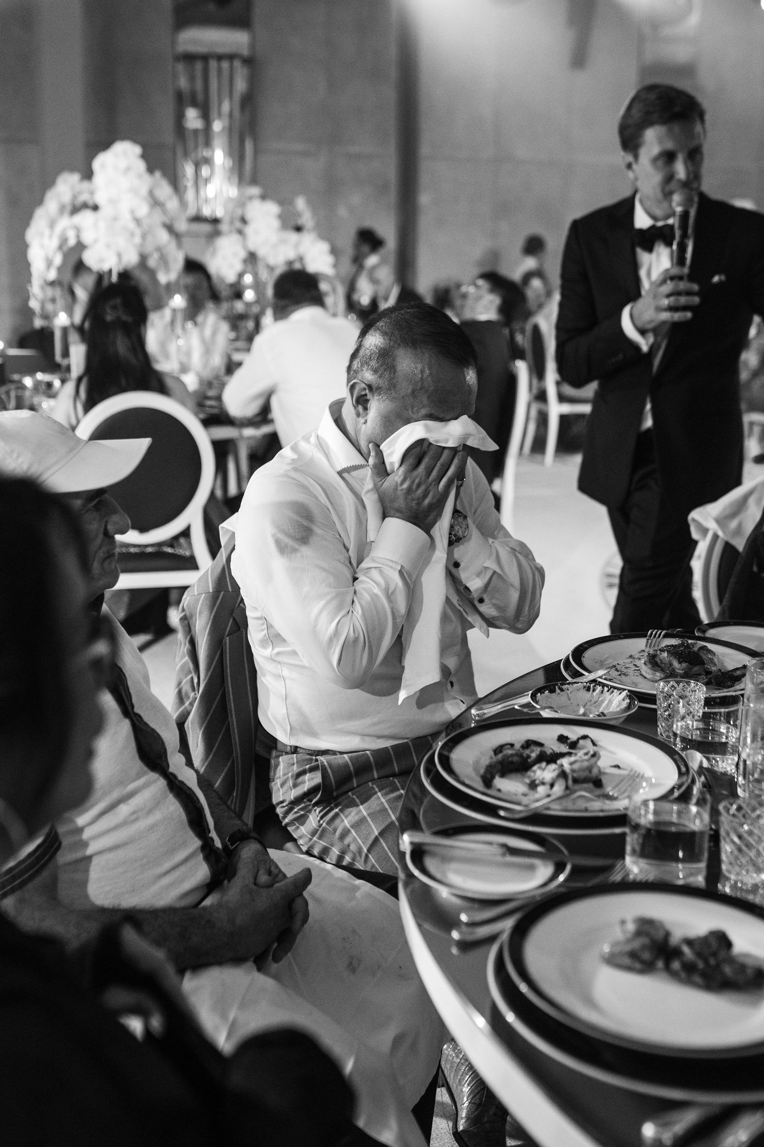 Black and white photo of guests dining at an elegant wedding reception.