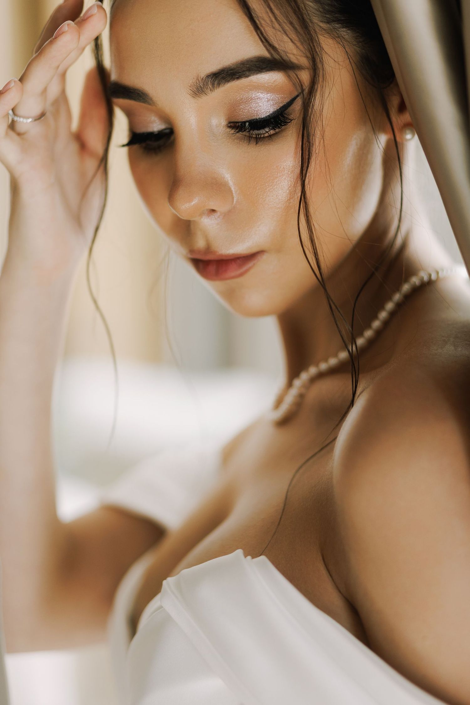 Elegant bridal portrait with soft lighting showcasing delicate pearl necklace and natural makeup.
