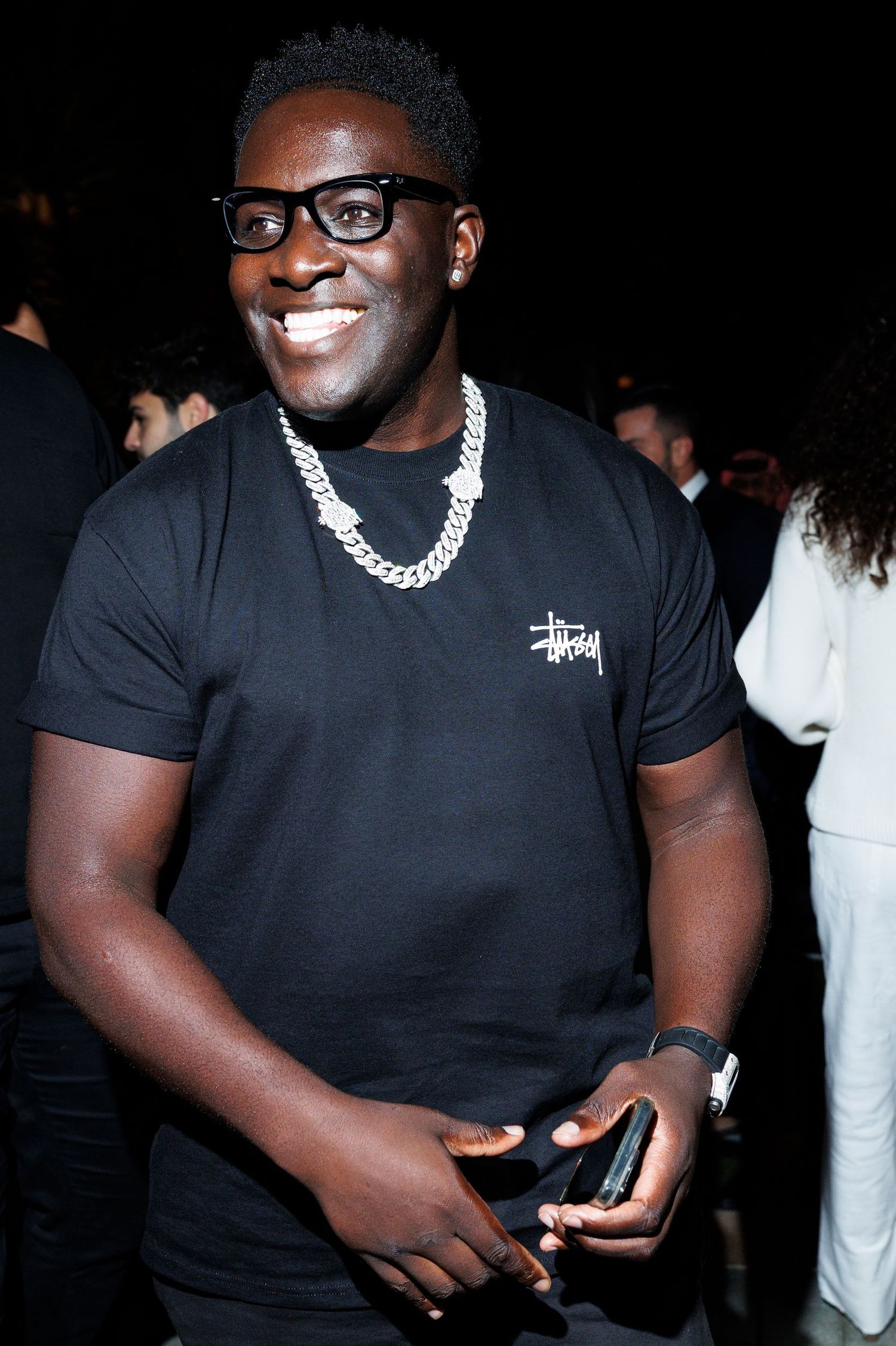 Person wearing black clothing and glasses at a nighttime event.