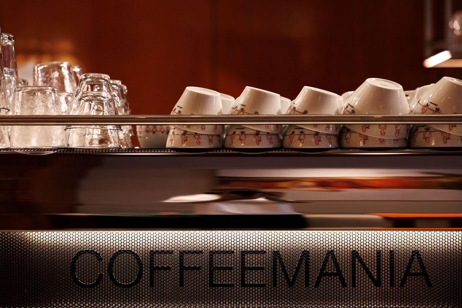 Coffee bar counter with neatly arranged cups and equipment under warm lighting.