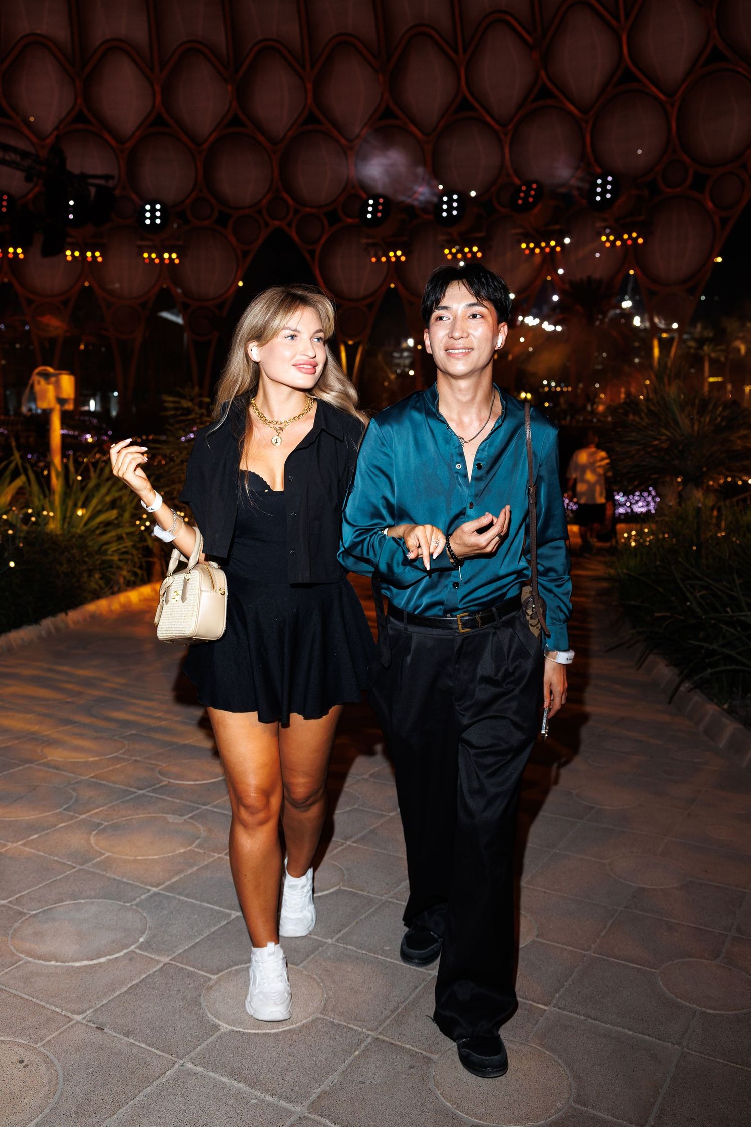 People in casual attire enjoying an evening outdoor event with ambient lighting.