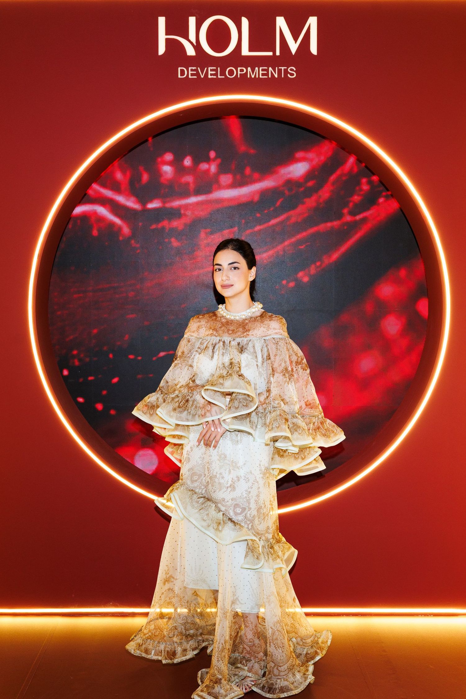 Fashion show backdrop featuring KOLM Developments logo with dramatic red and gold lighting effects.
