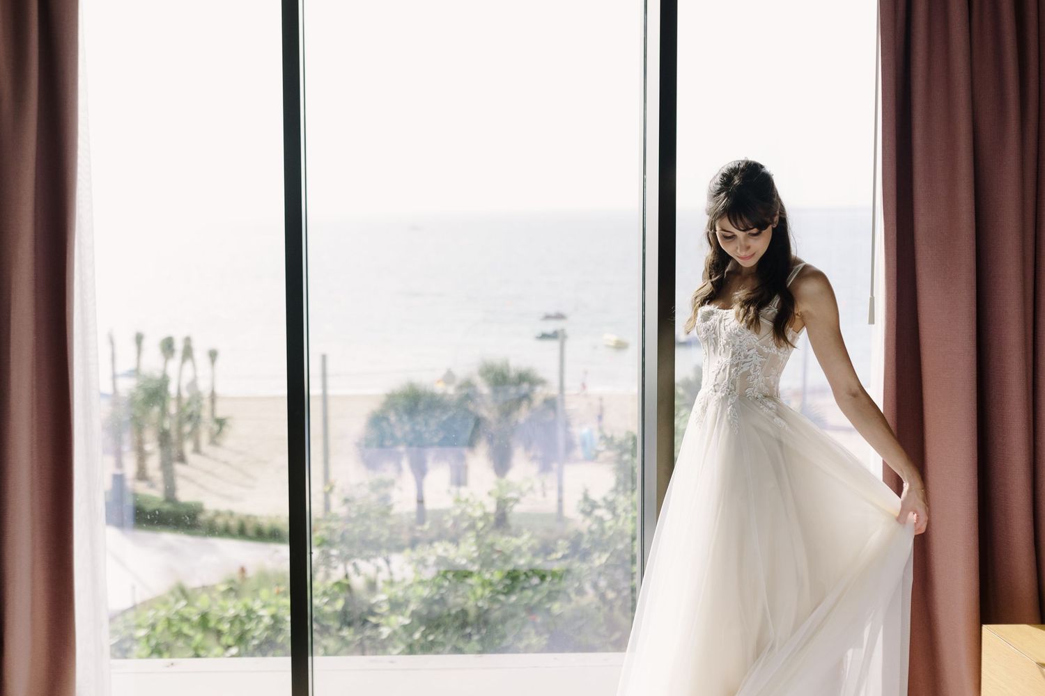 Sunlit bridal preparation room with large windows and flowing curtains.