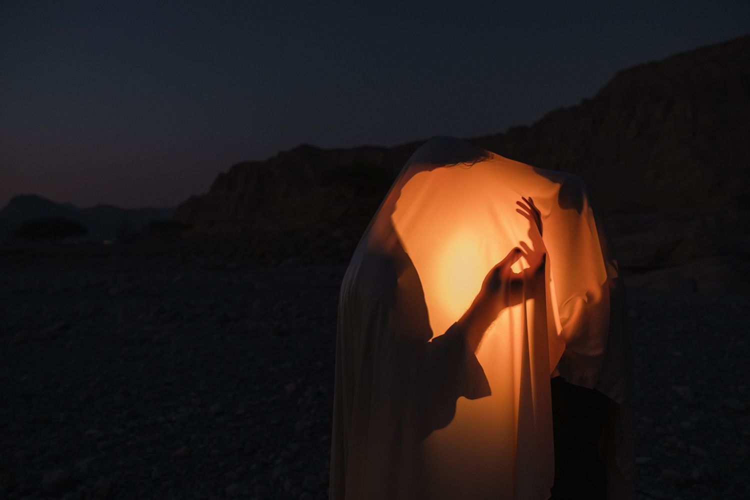 Orange fabric illuminated from behind creates a dramatic glowing effect against a dark background.