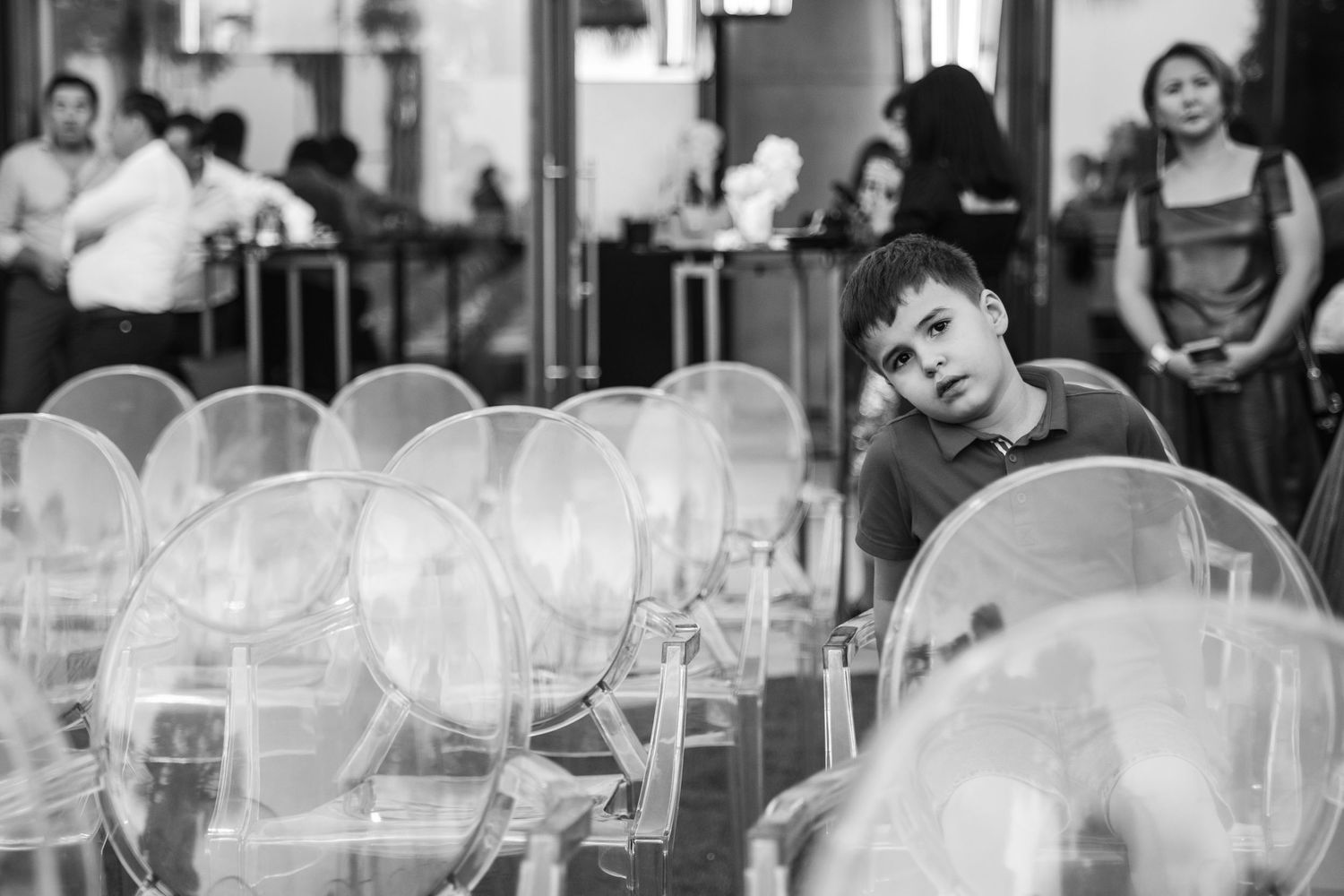 Black and white photo of clear ghost chairs arranged for an indoor event.