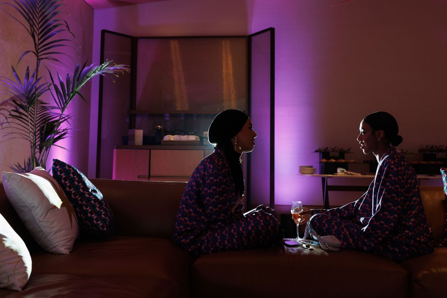 Room interior with purple mood lighting and palm plant silhouettes.