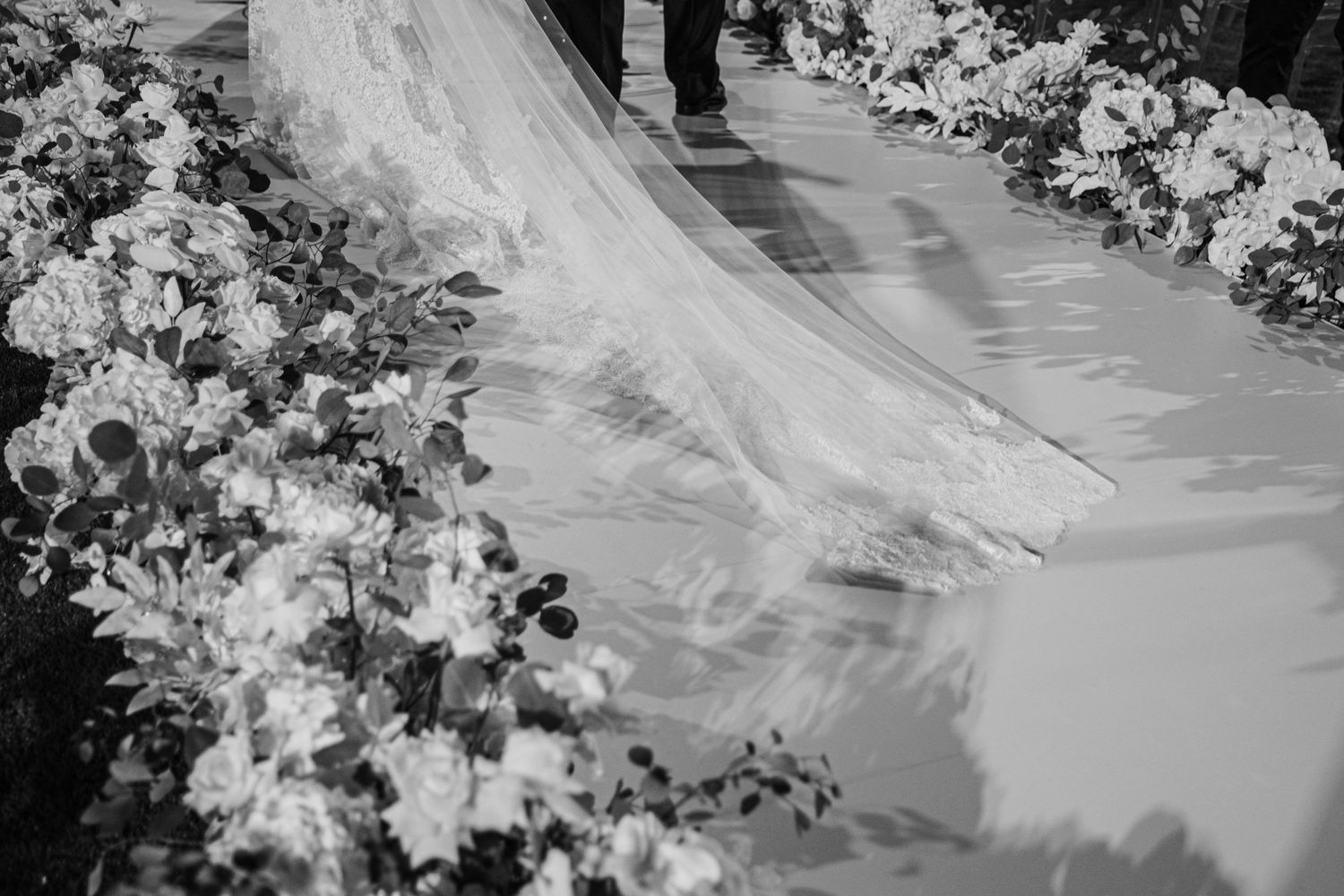 Elegant white wedding dress with flowing veil and delicate lace details in a bridal suite.